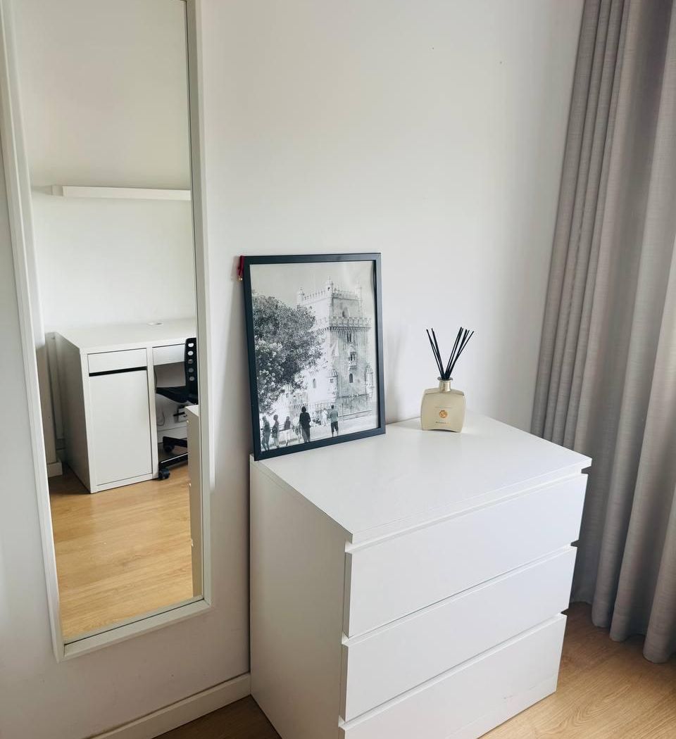 Full-length mirror next to a three-drawer chest, with a framed print of the Belém Tower on top.