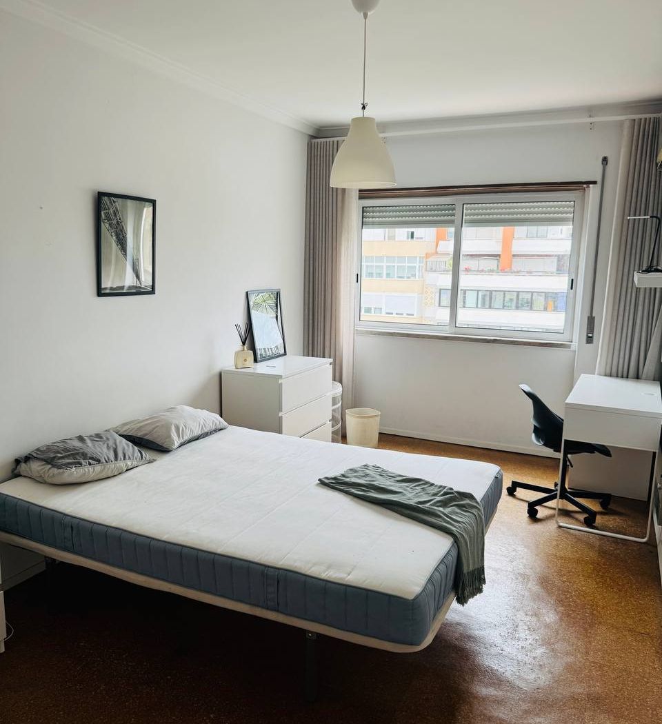 Double bed, chest of drawers and a desk by the window, which looks onto Avenida do Brasil.