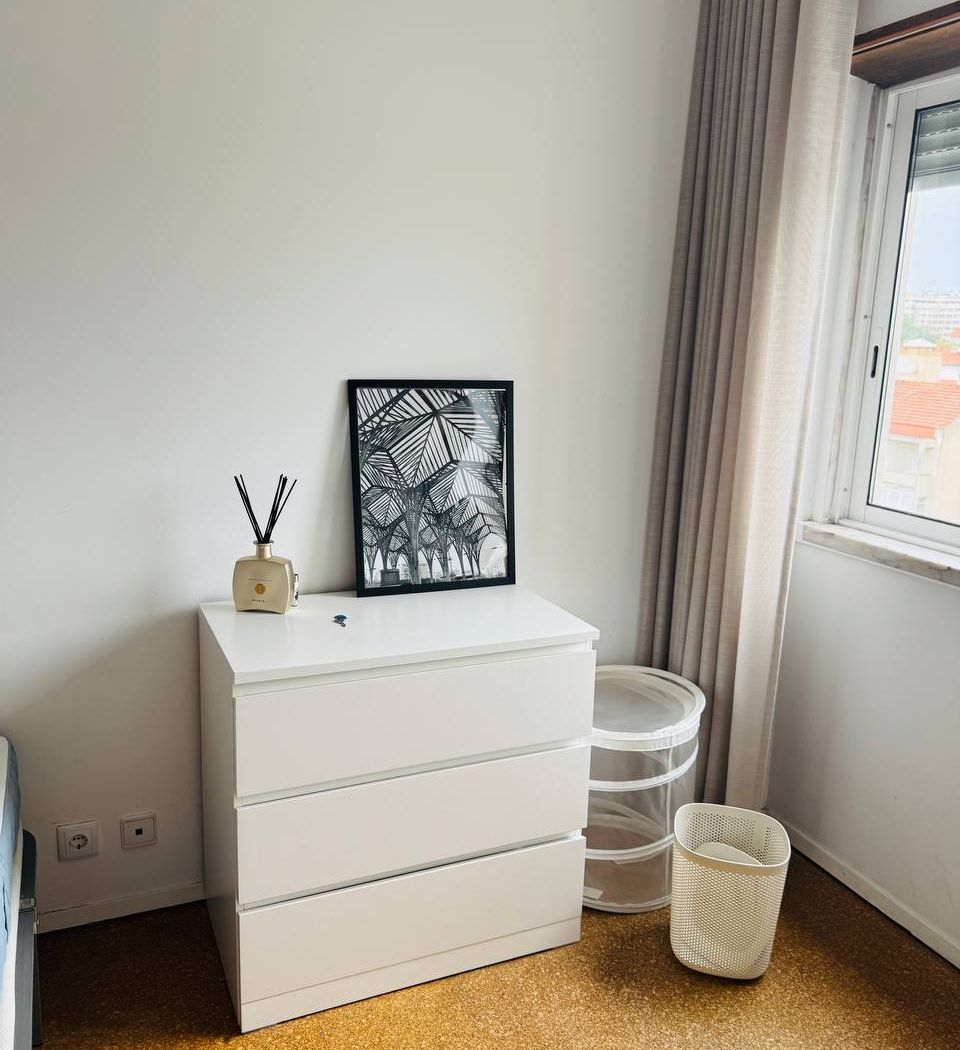 Chest of drawers with a framed print, next to the window and the laundry baskets.