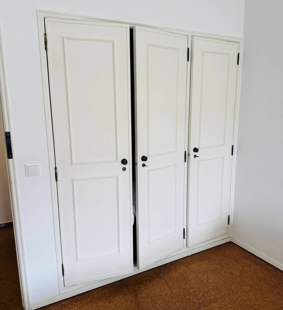 Built-in wardrobe with three doors, running the width of the wall.